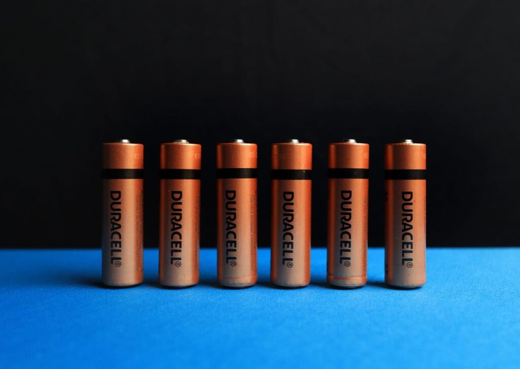 A lined up set of AA batteries with black and blue background.
